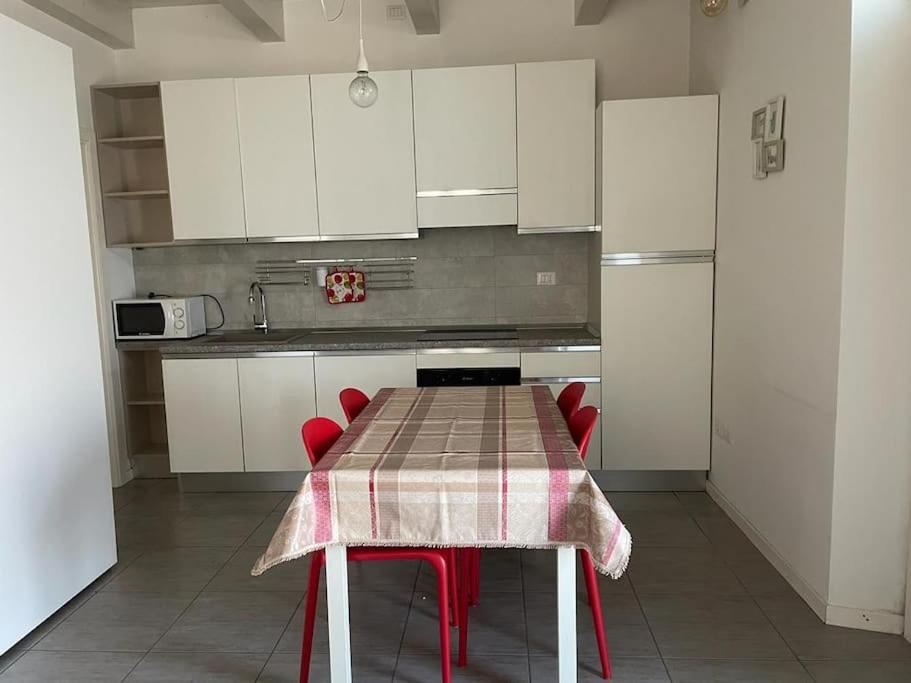 法诺Monolocale al porto的厨房配有带红色椅子的桌子和白色橱柜。