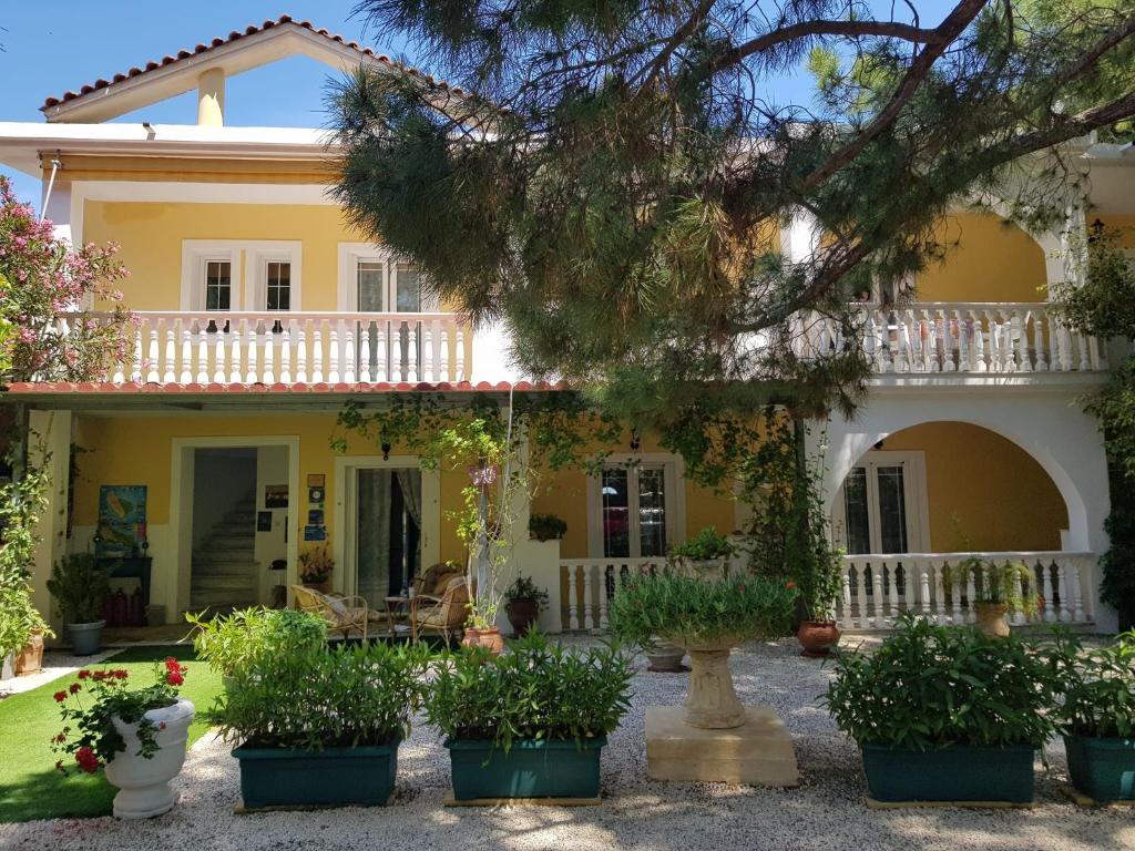 瓦西里科斯Kuris Studios & Apartments的前面有盆栽植物的黄色房子