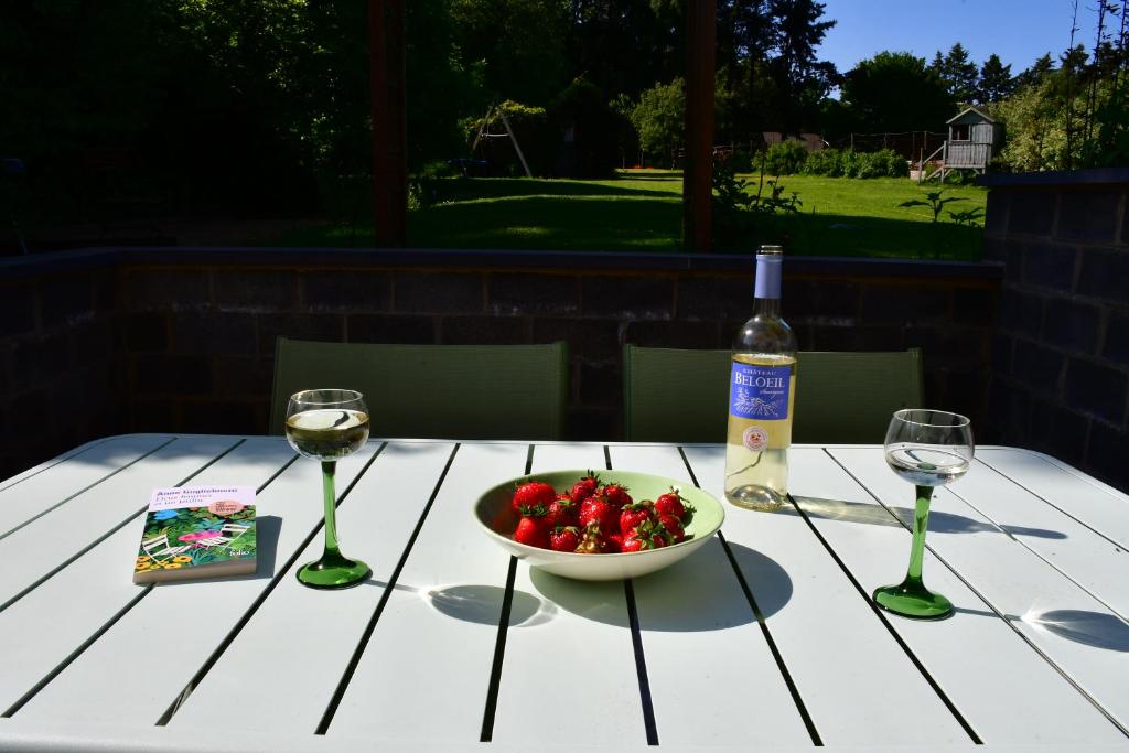 那慕尔Au four et au jardin的一张桌子,上面放着一碗草莓和一瓶葡萄酒