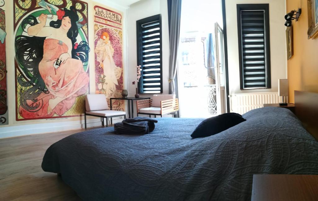 希迈Aux frais de la princesse - Gîte citadin 3 épis的卧室配有一张床,墙上挂有绘画作品