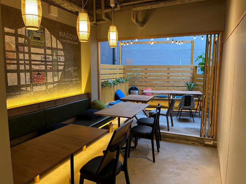 名古屋2023年6月開業 サカエ ゲストハウス的餐厅设有桌椅和大窗户。