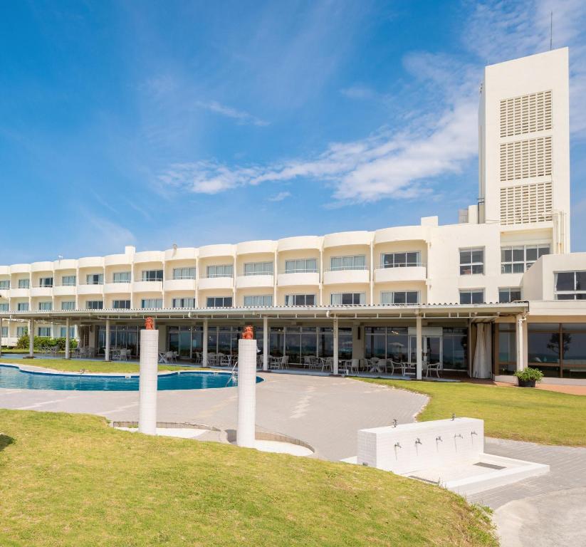 久米岛EN RESORT Kumejima EEF Beach Hotel的一座白色的大建筑,前面设有一个游泳池