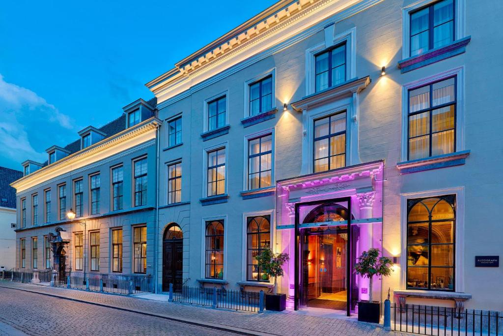 布雷达布雷达拿韶傲途格精选酒店的一条白色的大建筑,一条街道上有一个紫色的门廊