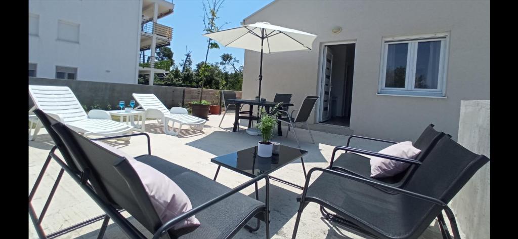 佩特坎内Apartman Punta Radman的庭院配有桌椅和遮阳伞。