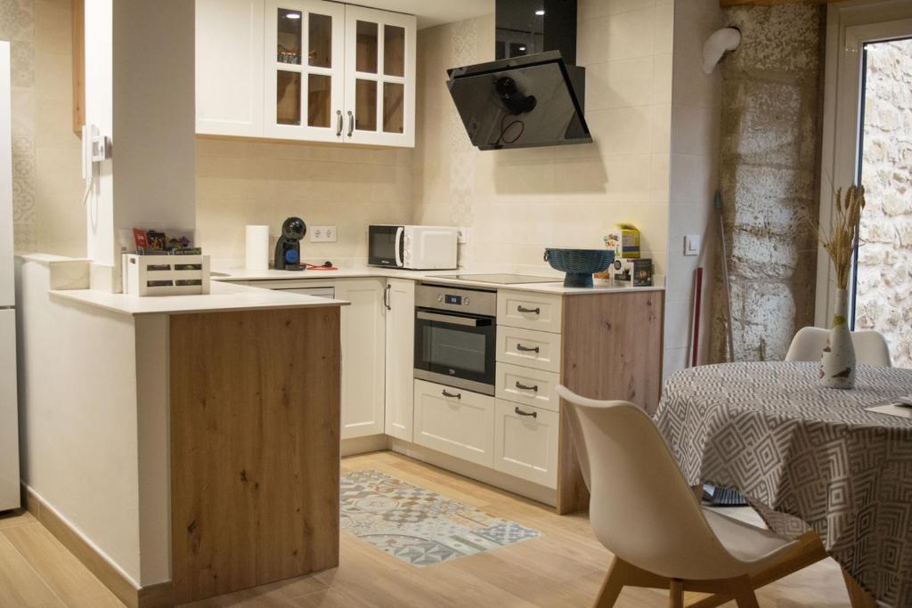 埃尔希耶戈En BLANCO y TINTO的厨房配有白色橱柜、桌子和椅子
