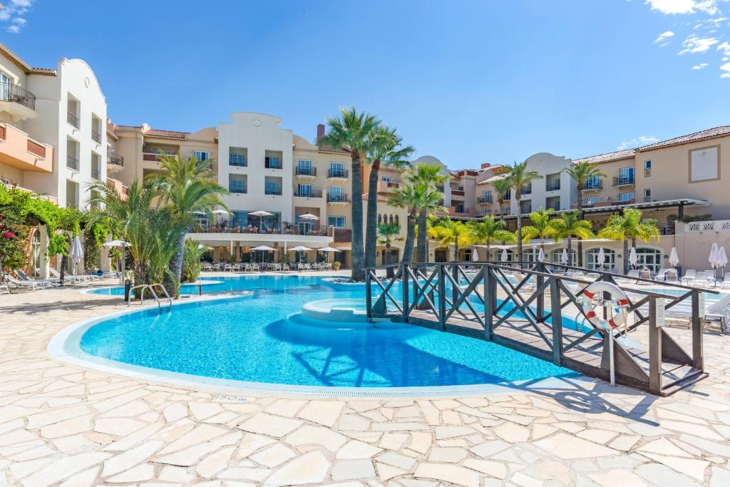 德尼亚Denia Marriott La Sella Golf Resort & Spa的棕榈树和建筑的度假村游泳池