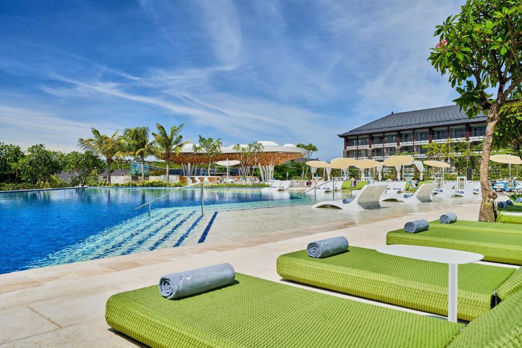 努沙杜瓦Renaissance Bali Nusa Dua Resort的一座带绿椅的度假村游泳池和一座建筑