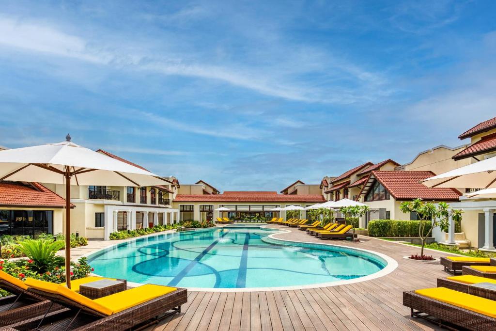 比纳里姆Fairfield by Marriott Goa Benaulim的度假村的游泳池,配有椅子和遮阳伞