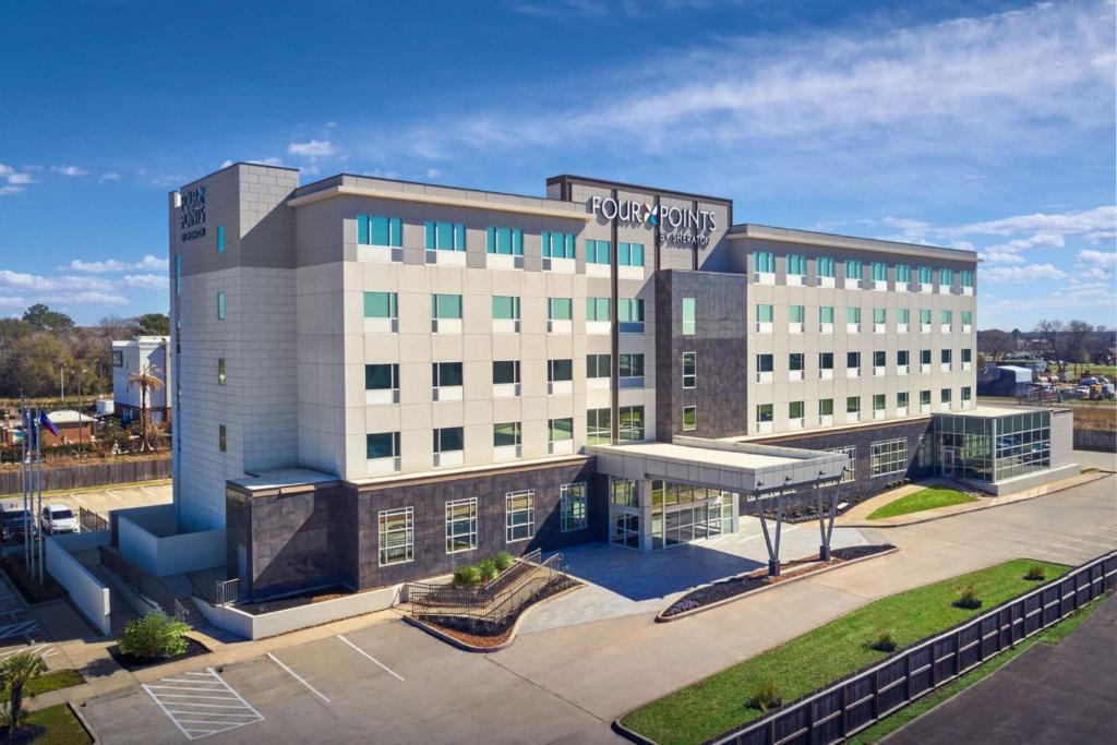 休斯顿Four Points by Sheraton Houston Intercontinental Airport的一座大型建筑,前面设有停车场