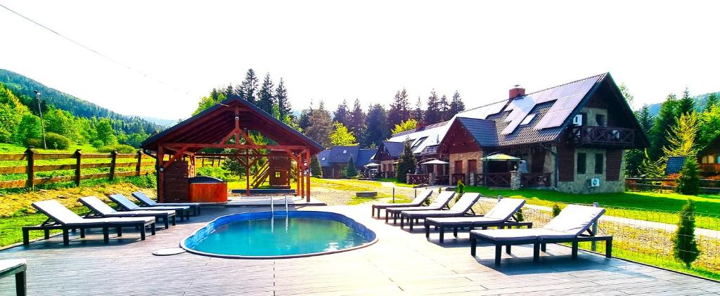 科尔别卢夫Ośrodek Wczasowy Na Borach的一个带椅子的庭院、一个游泳池和一个房子