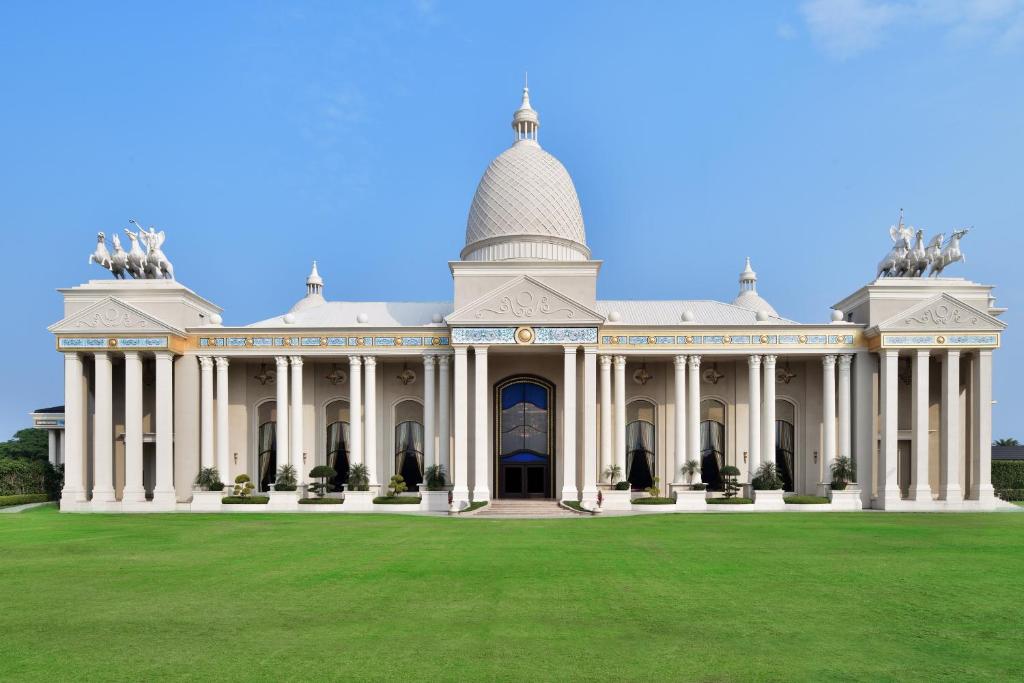印多尔Sheraton Grand Palace Indore的一座白色的大建筑,设有绿色草坪
