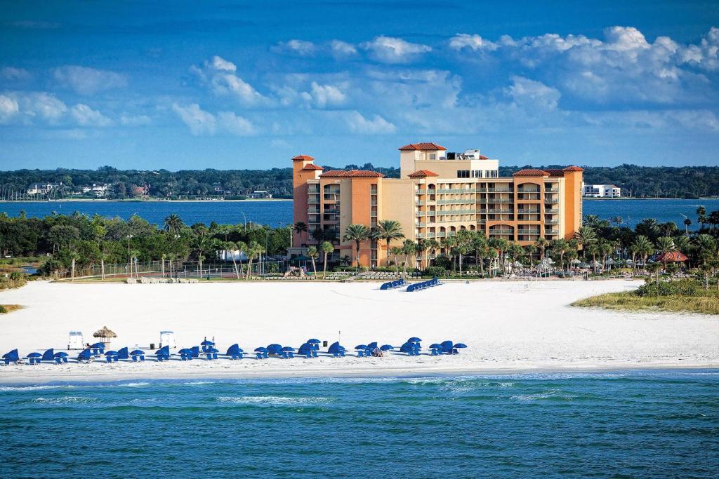 克利尔沃特Sheraton Sand Key Resort的一个带椅子和遮阳伞的海滩和一家酒店