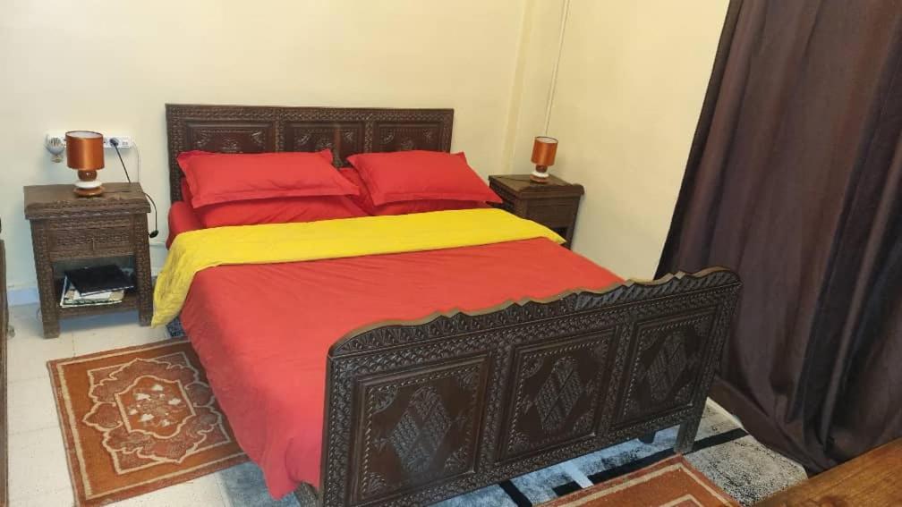 阿尔及尔Bel appartement proche de l'aéroport的卧室内的一张大床,配有红色和黄色枕头