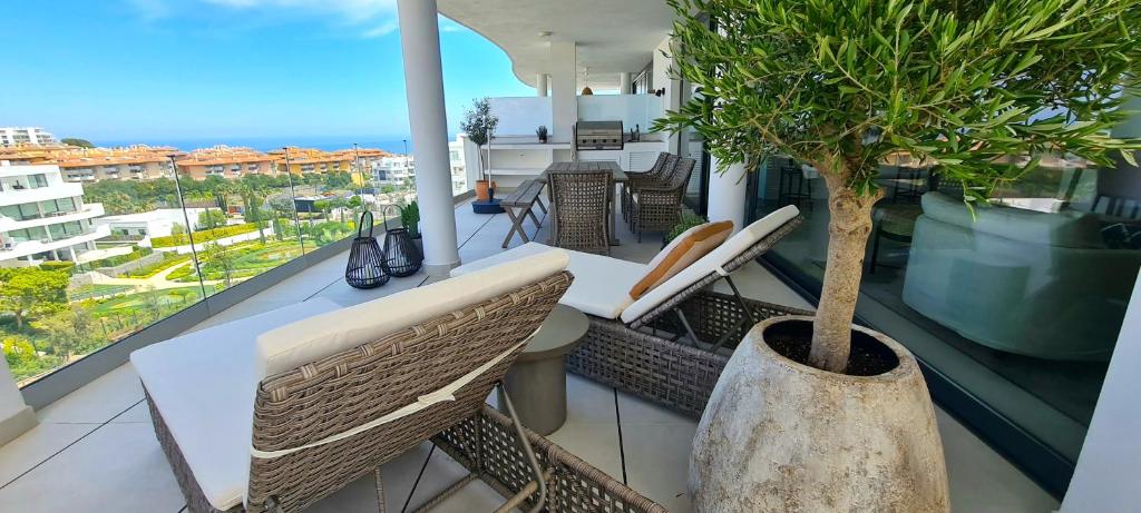 福恩吉罗拉Mara's Apartments Higueron West - Scandinavian Luxury - Views of the Sea and Natural Landscapes的阳台配有桌椅和一棵树。