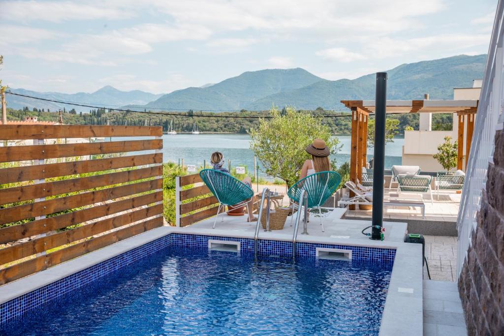 蒂瓦特Villa Gioia的一座游泳池,两位客人坐在房子旁边的椅子上
