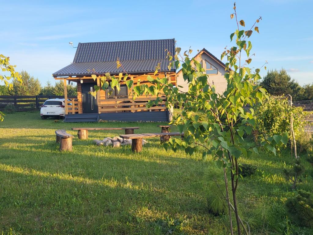 JedwabnoPrzytulny domek w Brajnikach 86 37的田野上的房子,有长凳的院子