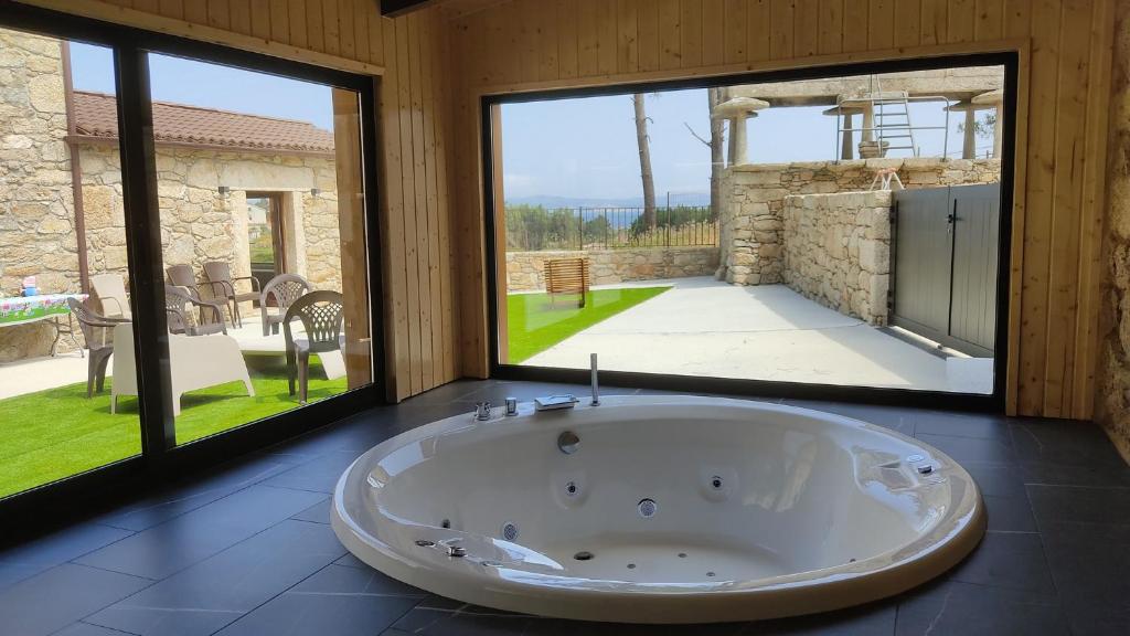 拉赫A Casa de Elisa的设有一个大浴缸,位于带大窗户的房间里