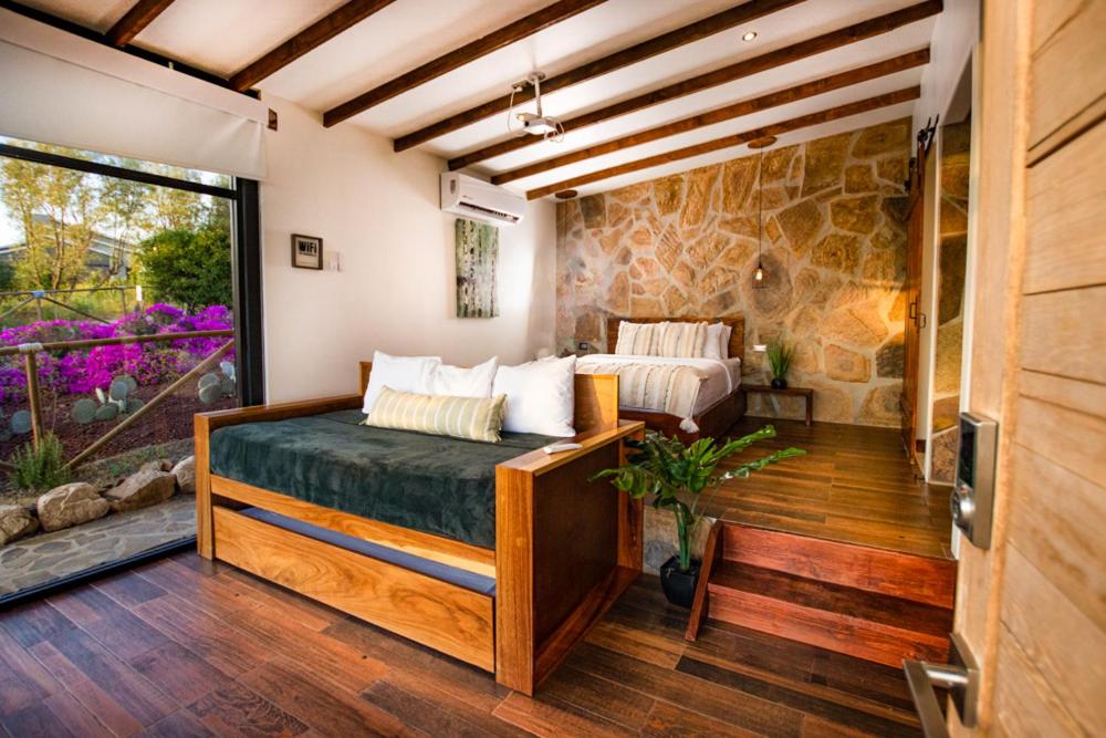 瓜达鲁佩镇Brisa Del Valle Hotel Boutique的一间卧室设有一张床和石墙