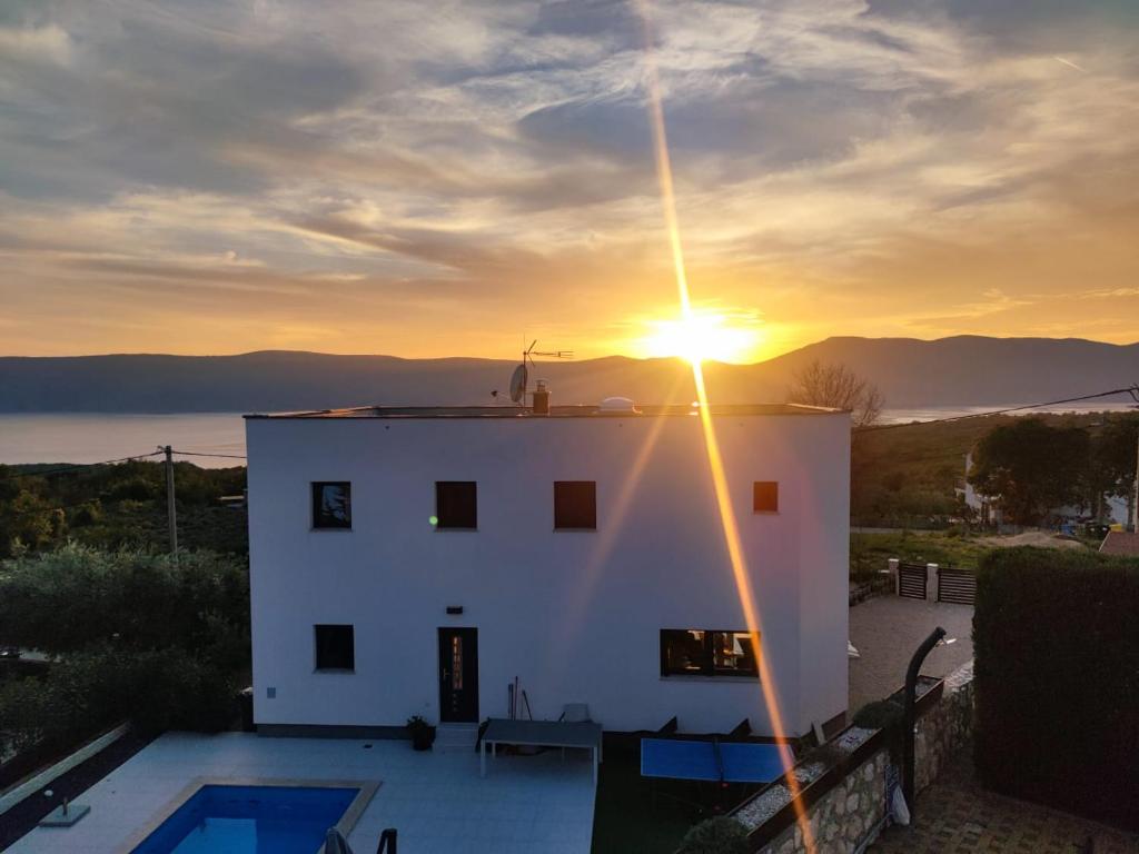 利纳迪奇Villa Alma Krk的白房子的日落美景,设有游泳池