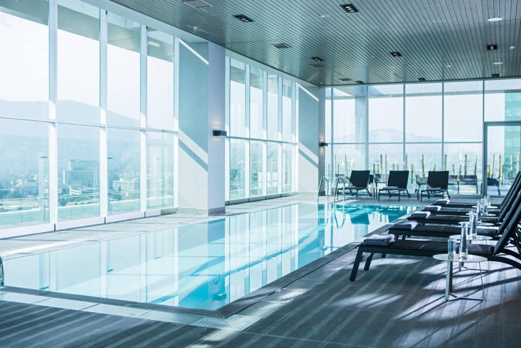 圣地亚哥圣地亚哥拉斯孔德斯万怡酒店的一座带椅子和窗户的游泳池