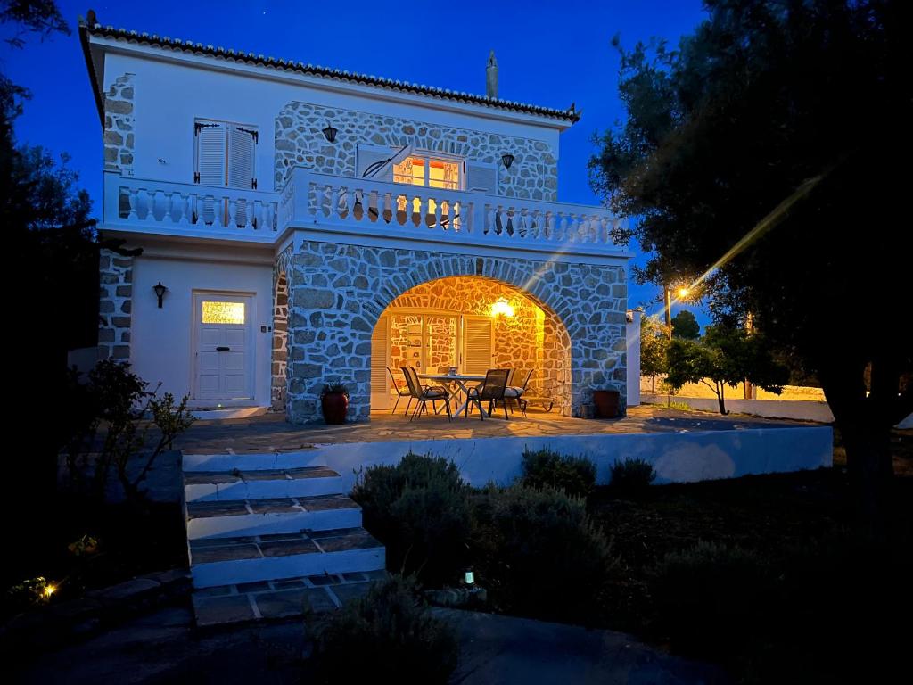 斯派赛斯Villa Ancora Spetses的夜晚在房子前面有桌子