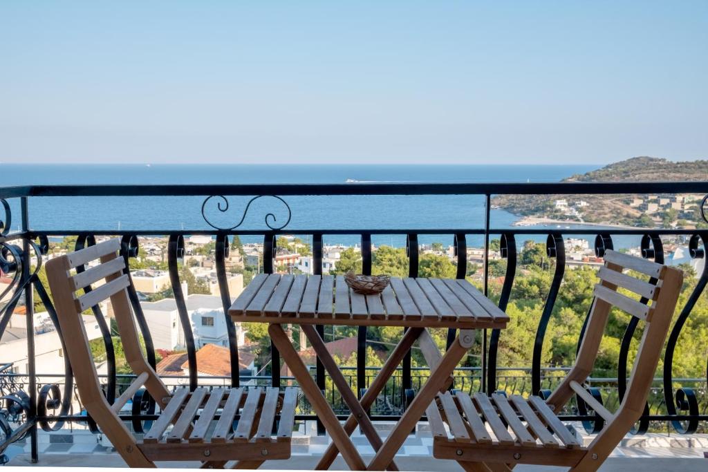 阿吉亚玛丽娜Pefkides Aegina Boutique Apartments的阳台上配有一张木桌和两把椅子