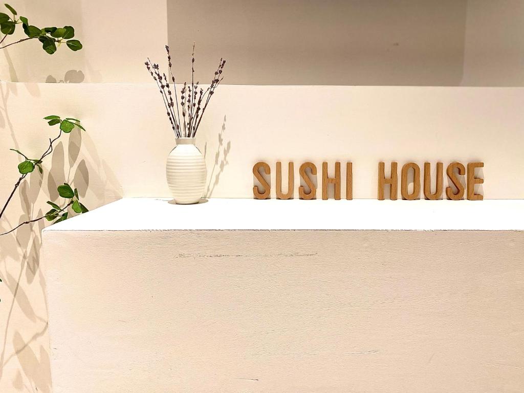 河内Sushi Old Corner homestay No16 Lane38 Hang Bun St的一张在柜台上加花瓶的寿司屋的标志