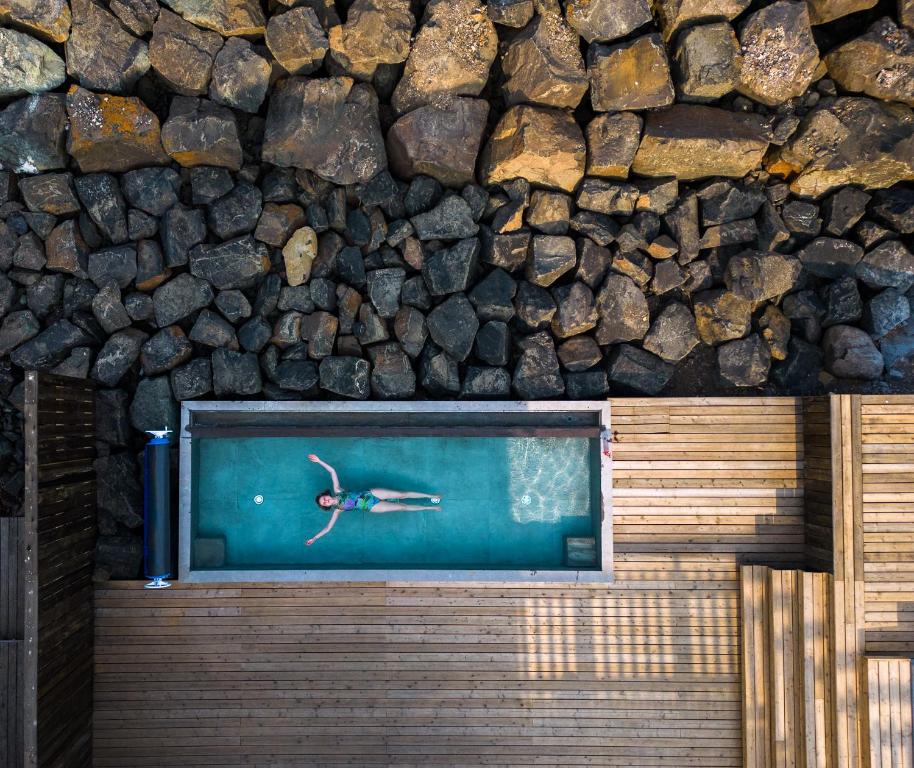 东博尔加峡湾Blabjorg Resort的在岩石墙旁边的游泳池游泳的人