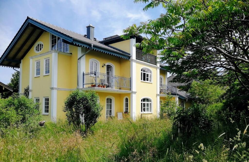 基姆湖畔格斯塔特Ferienwohnung in seenaher Künstlervilla in Gstadt的黄色房子的一侧设有阳台