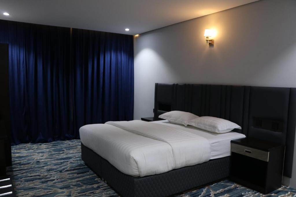 艾卜哈قمم بارك Qimam Park Hotel 4的卧室配有一张带蓝色窗帘的大型白色床