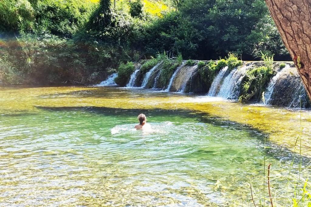 PadernGîte de la confluence的瀑布前的游泳池游泳的人