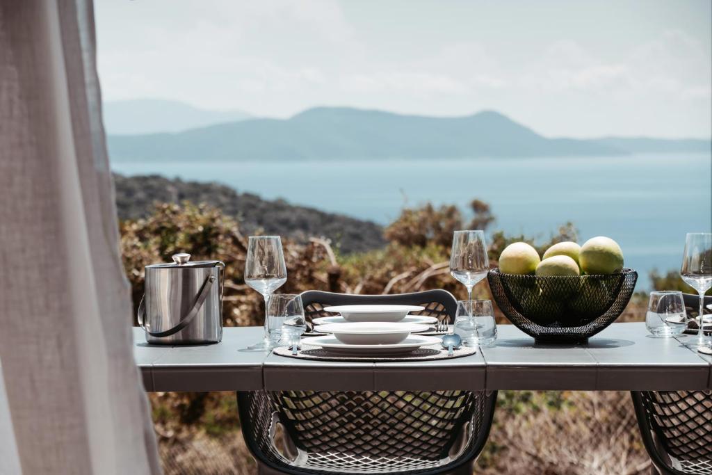 梅加尼西岛Mesogi Villas, brand new modern, stylish villas, private pool, seaviews的一张桌子,上面放着一碗水果和酒杯