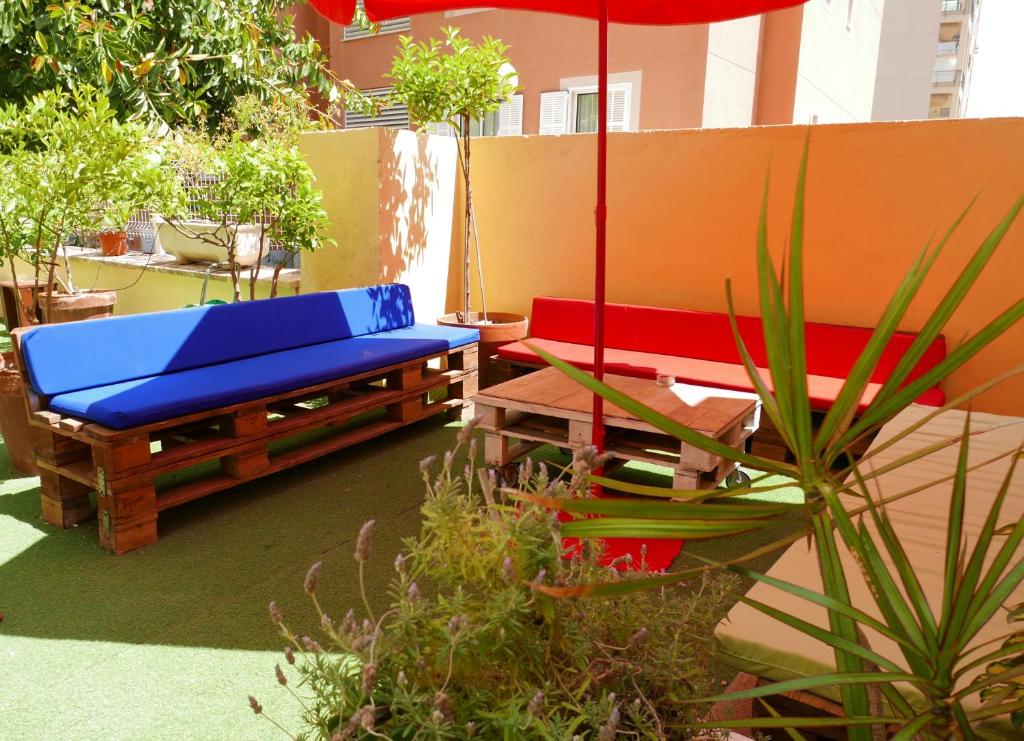 马略卡岛帕尔马帕尔马港旅舍 - 青年旅舍的庭院设有2张长椅和遮阳伞。