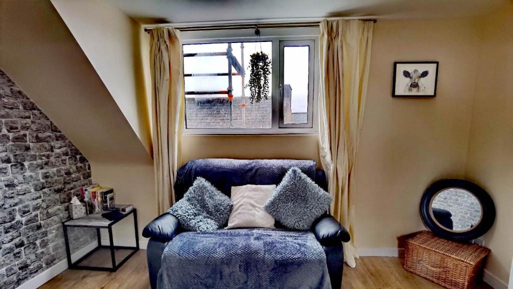 奥克尼Cozy Loft In The Heart Of Kirkwall的窗户客房内的蓝色沙发