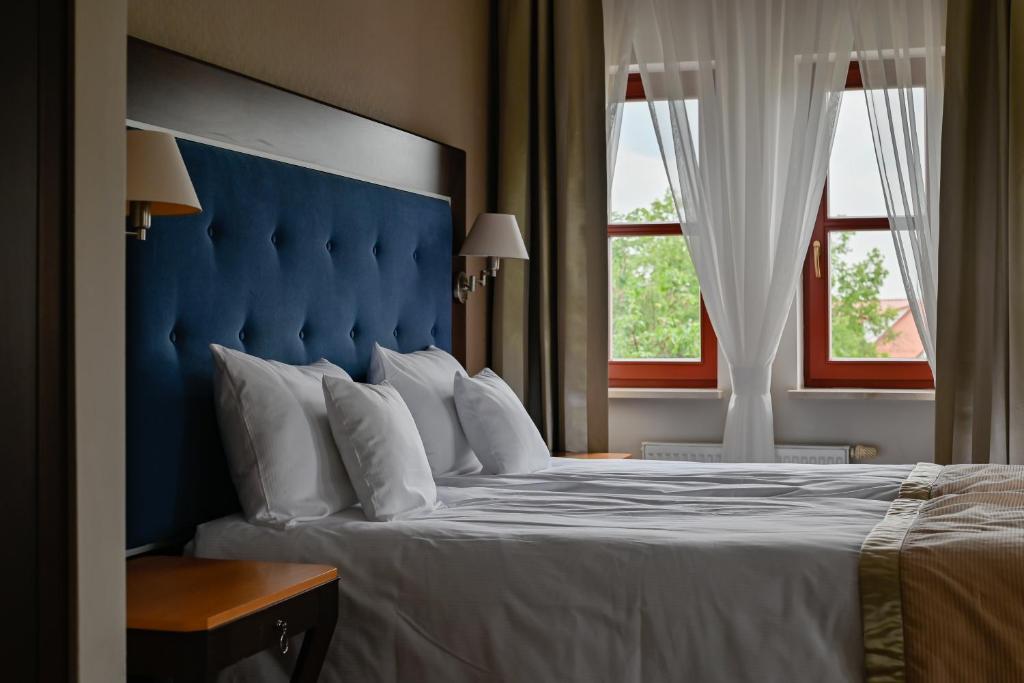 奥尔什丁Villa Garden Dyplomat的一张带蓝色床头板的床和两个窗户