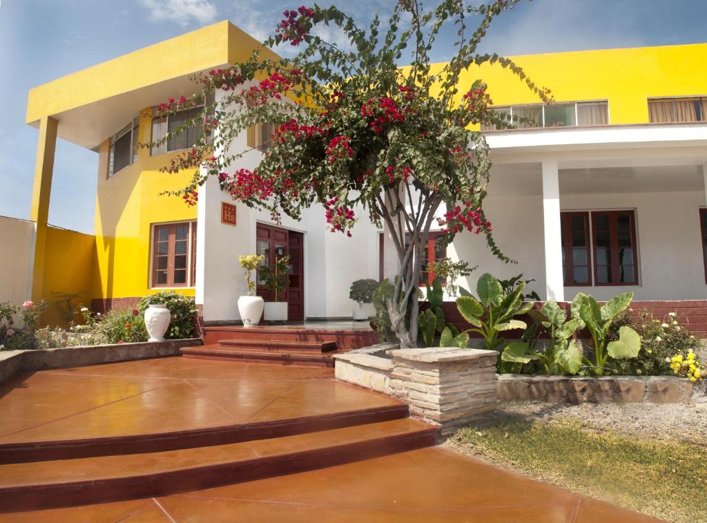 皮斯科米拉玛旅舍的黄色和白色的房子,有树和鲜花