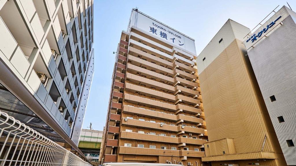 大阪Toyoko Inn Osaka Umeda Higashi的一座高大的建筑,上面有标志