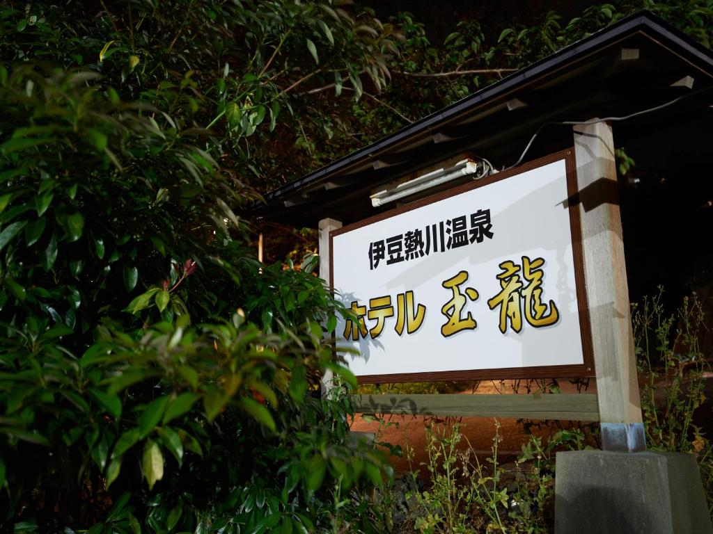 东伊豆町Tabist Izu Atagawa Onsen Hotel Gyokuryu的树旁餐馆的标志