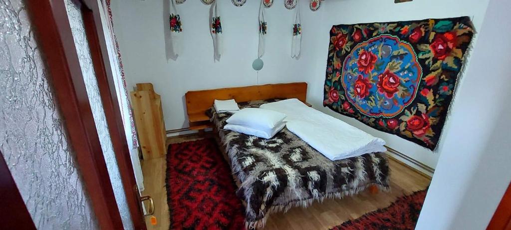 瓦杜伊泽Pensiunea La Gorgan的一间小卧室,配有一张床和墙上的绘画