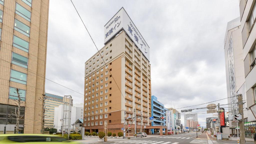 大分Toyoko Inn Oita Ekimae的一座高大的建筑,上面有标志