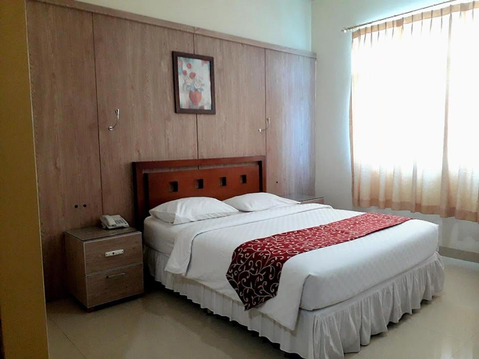 索龙THE IGNISLO HOTEL SORONG的一间卧室配有一张大床,铺有红白毯子