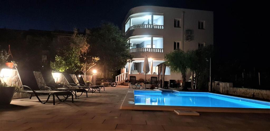 罗戈兹尼察Villa Stella的一座游泳池,在晚上在建筑物前