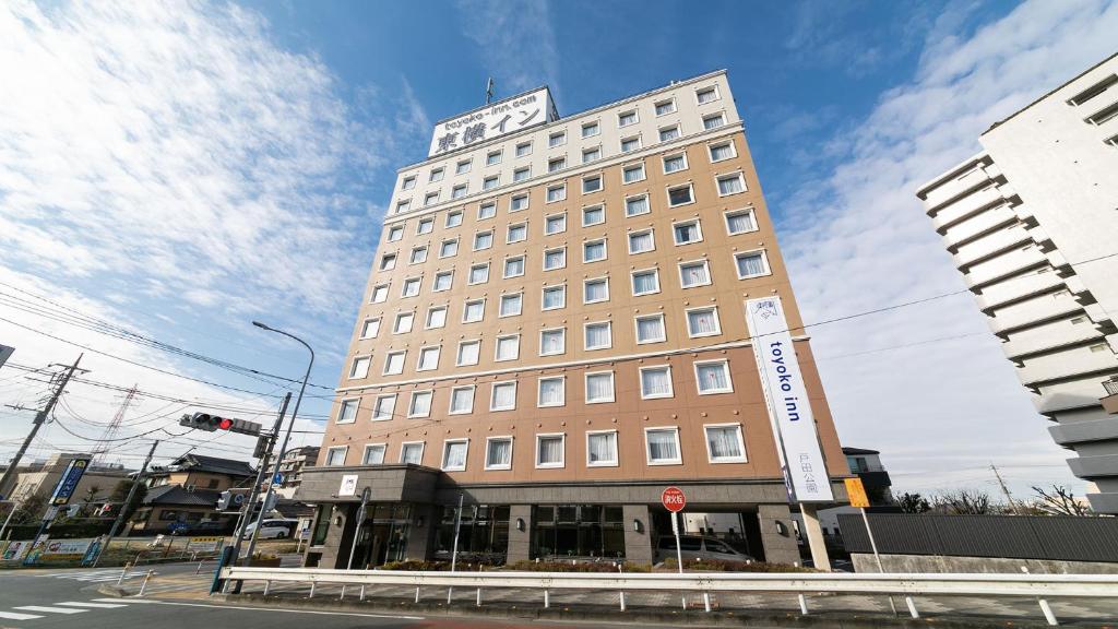 户田市Toyoko Inn Saitama Toda koen eki Nishi guchi的一座高大的建筑,上面有钟