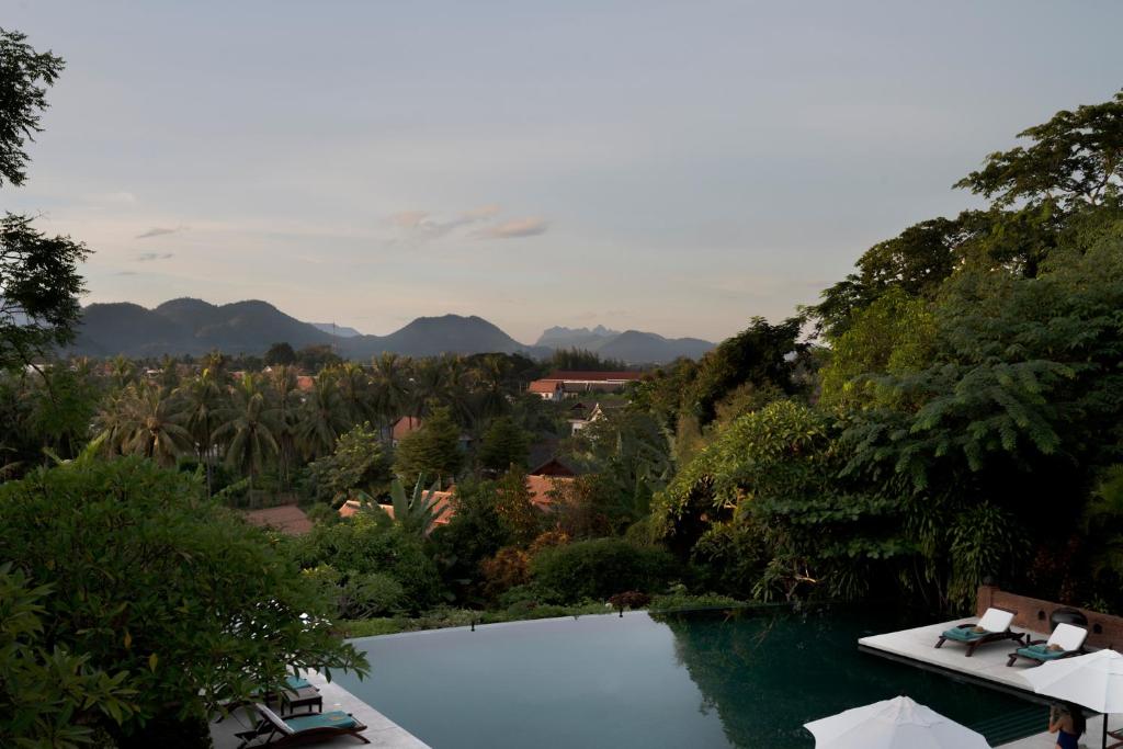 琅勃拉邦La Résidence Phou Vao, A Belmond Hotel, Luang Prabang的一座位于花园内的游泳池,花园内以群山为背景