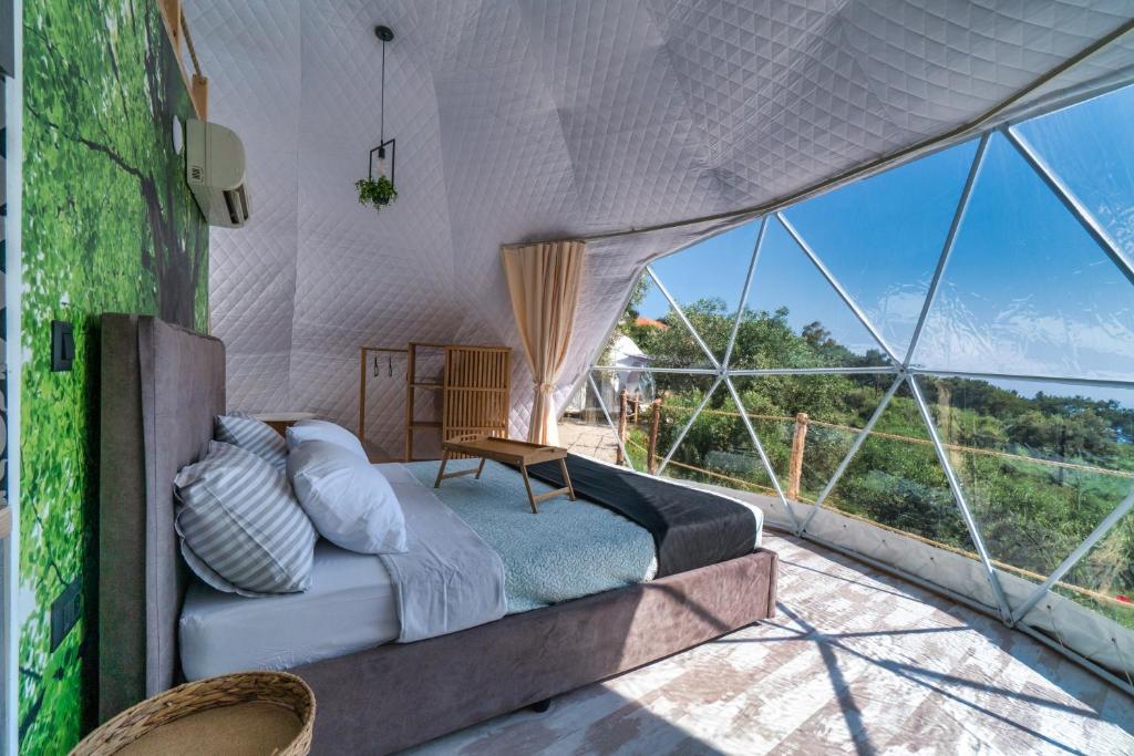 Rachesluxury dome tents ikaria ap'esso的一个带大窗户的帐篷内一间卧室,配有一张床