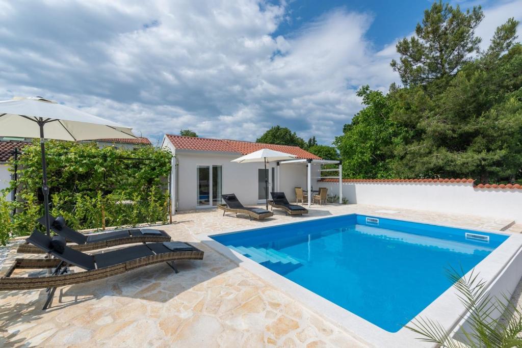 波雷奇Casa Cosini with Private Pool的房屋旁的游泳池配有椅子和遮阳伞