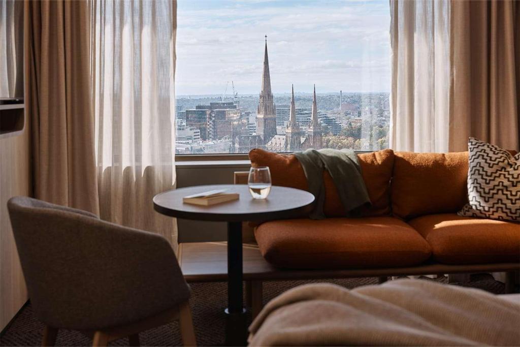 墨尔本墨尔本雷吉斯中央商务区酒店的客厅配有沙发和一张桌子及一杯葡萄酒