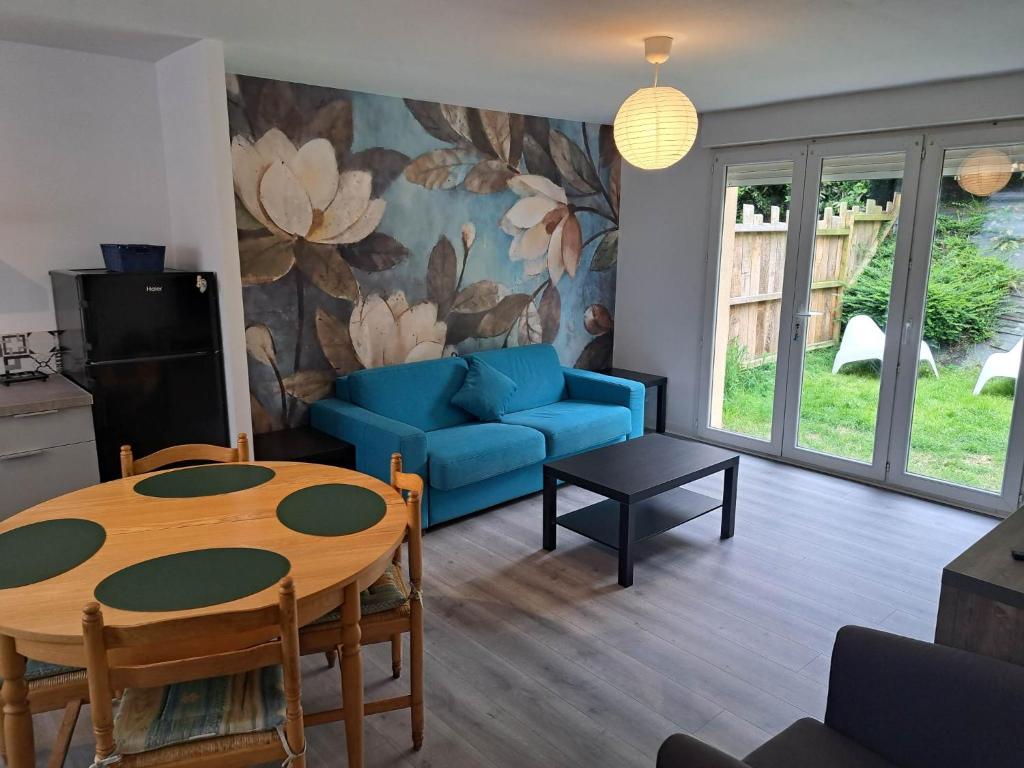 拉尼翁Appartements Lannion proche centre, Côtes de Granit Rose的客厅配有桌子和蓝色沙发