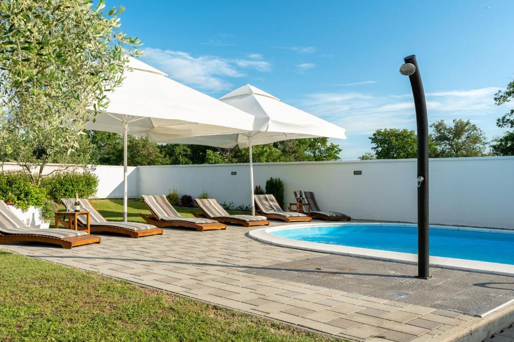 伽罗瓦克House Leonardo的一个带椅子和遮阳伞的庭院和一个游泳池