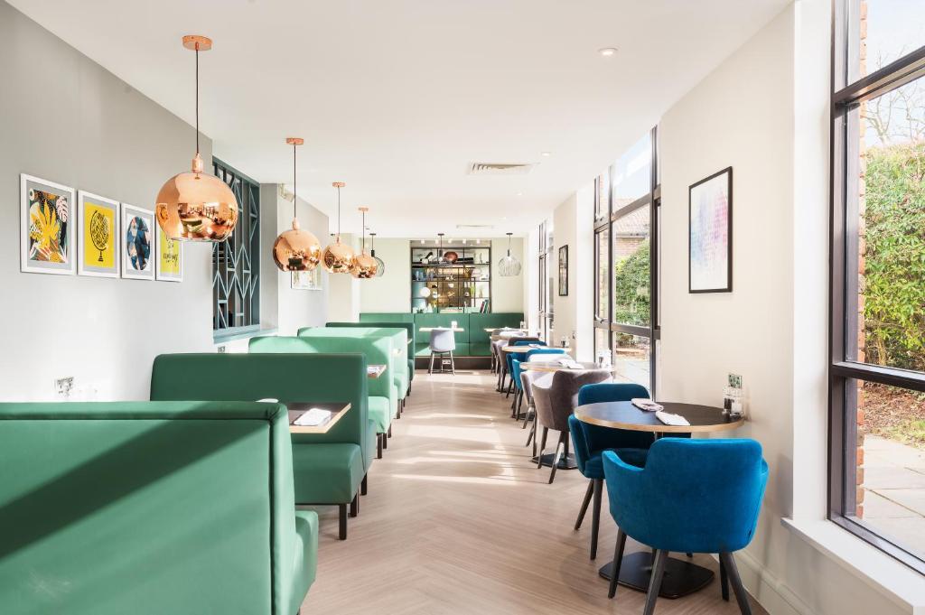 查塔姆罗切斯特查塔姆酒店的用餐室配有绿色的椅子和桌子
